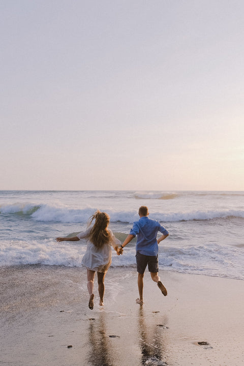 Two people running on a beach with waves in the background